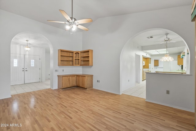 unfurnished living room with vaulted ceiling, light hardwood / wood-style floors, and ceiling fan with notable chandelier