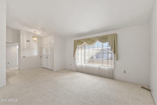 carpeted spare room featuring an inviting chandelier