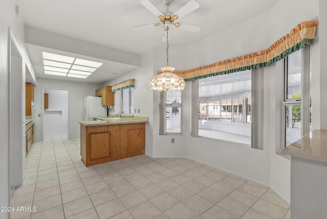 kitchen with kitchen peninsula, ceiling fan, light tile patterned flooring, and white refrigerator