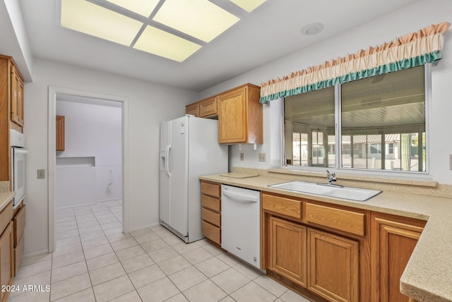 kitchen featuring light tile patterned floors, white appliances, and sink