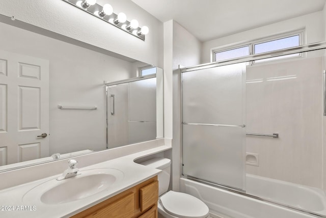 full bathroom featuring vanity, toilet, and shower / bath combination with glass door