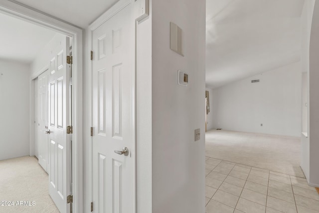 hallway with light colored carpet and vaulted ceiling