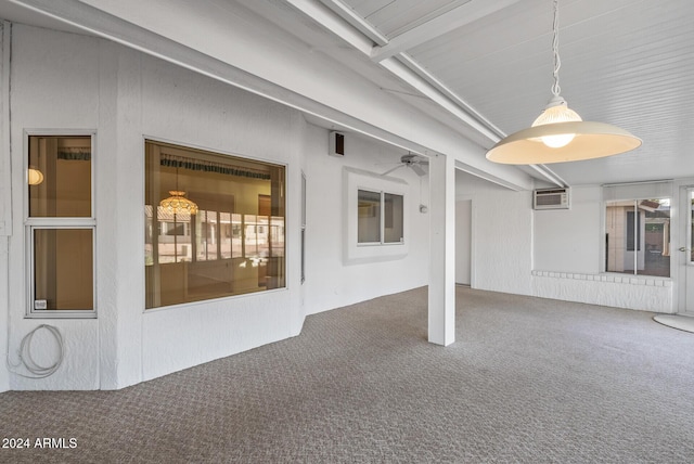 interior space with carpet, a wall mounted air conditioner, ceiling fan, and a healthy amount of sunlight