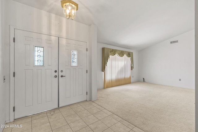 carpeted foyer entrance featuring a chandelier and lofted ceiling