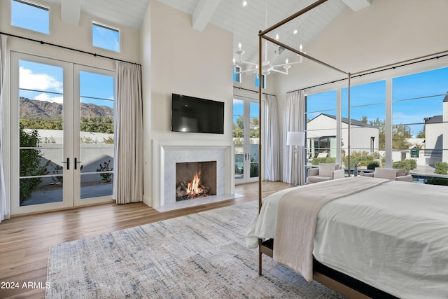 bedroom featuring beamed ceiling, light hardwood / wood-style flooring, high vaulted ceiling, and french doors