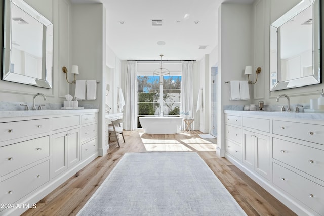 bathroom with a tub to relax in, hardwood / wood-style floors, and vanity