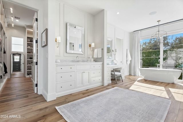 bathroom with a washtub, wood-type flooring, vanity, and a chandelier