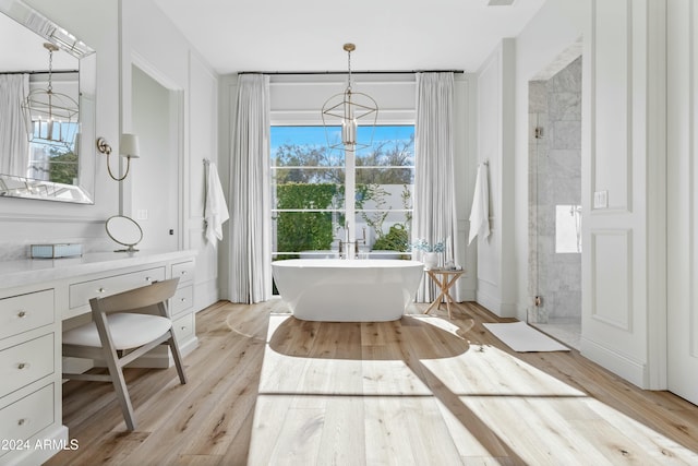 bathroom featuring vanity, wood-type flooring, shower with separate bathtub, and an inviting chandelier