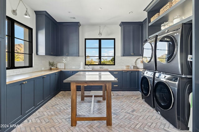 clothes washing area featuring sink, cabinets, and stacked washer / drying machine