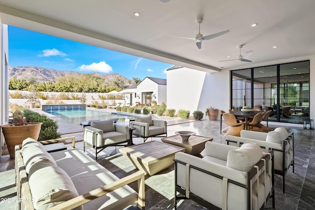 view of patio with a mountain view, an outdoor hangout area, a fenced in pool, and ceiling fan