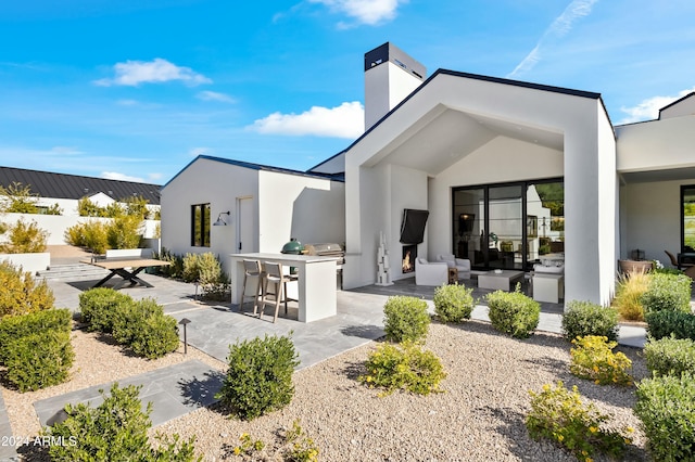 back of house featuring outdoor lounge area, a patio, an outdoor bar, and exterior kitchen