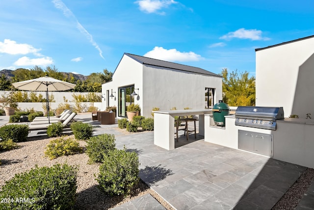 view of patio / terrace with a grill, a mountain view, and an outdoor kitchen