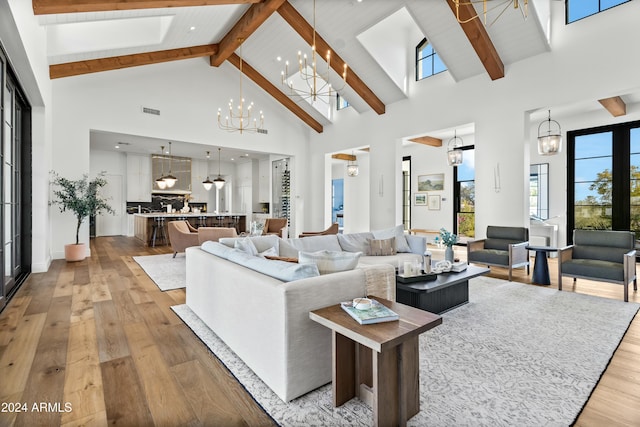 living room with beam ceiling, an inviting chandelier, high vaulted ceiling, and light wood-type flooring