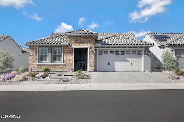 view of front of home with concrete driveway, an attached garage, a tile roof, and stucco siding