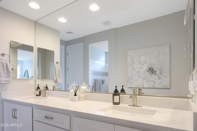 full bath with double vanity, visible vents, and a sink