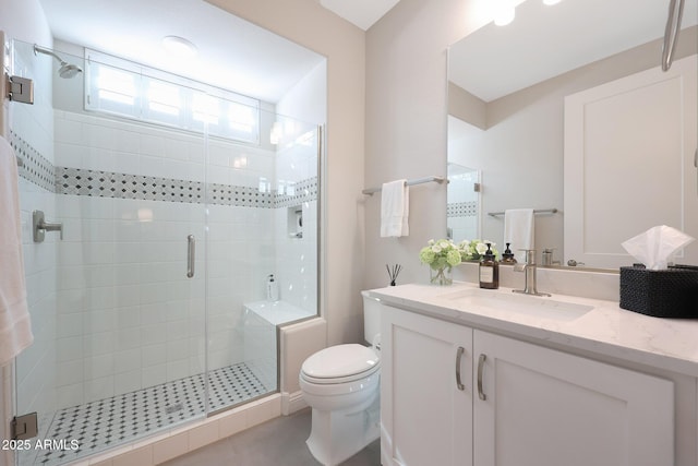 bathroom featuring vanity, a shower stall, and toilet