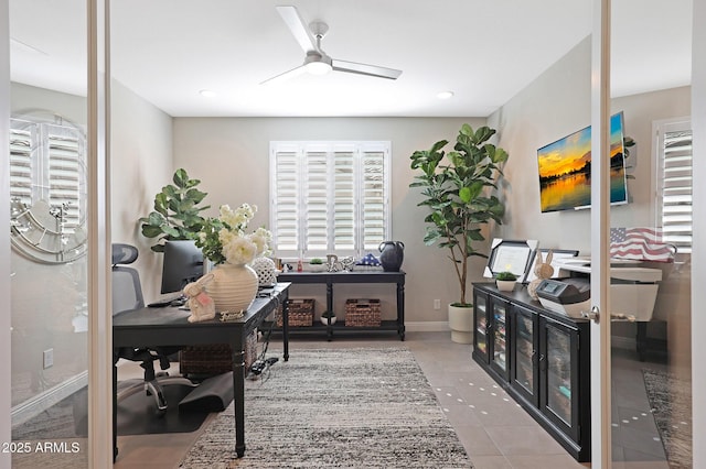 tiled office space with ceiling fan and baseboards