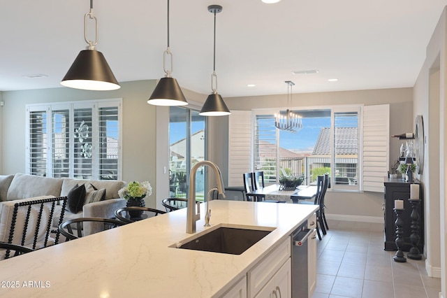 kitchen featuring light tile patterned floors, light stone counters, a sink, decorative light fixtures, and an inviting chandelier