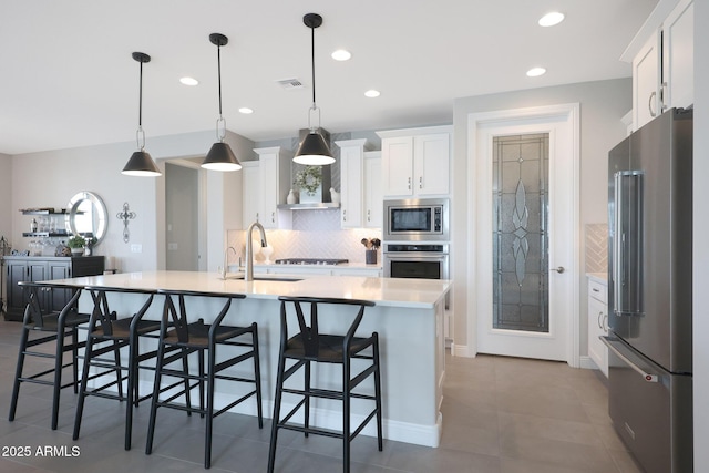 kitchen featuring stainless steel appliances, tasteful backsplash, light countertops, visible vents, and white cabinetry