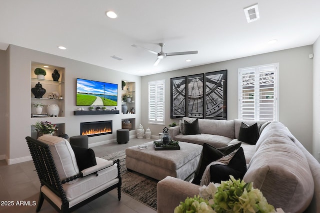 living area featuring a lit fireplace, built in shelves, visible vents, and recessed lighting