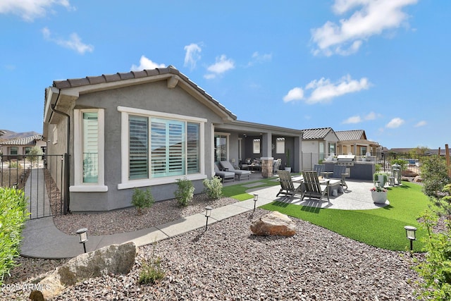 rear view of property with a patio area, fence, a lawn, and stucco siding