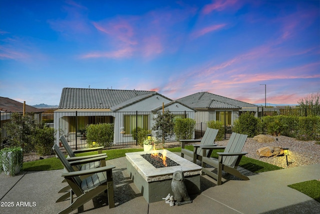 exterior space featuring a patio area, a fenced backyard, a tile roof, and a fire pit