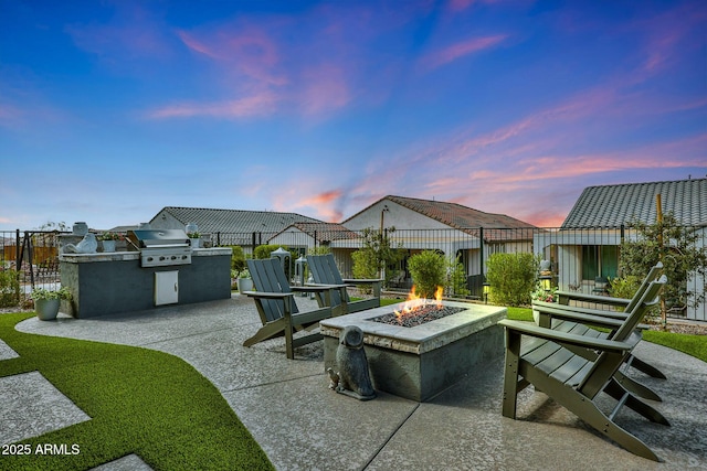 view of patio featuring exterior kitchen, a fire pit, fence, and grilling area