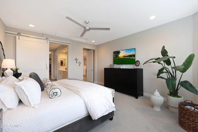 bedroom featuring recessed lighting, a barn door, connected bathroom, and light colored carpet