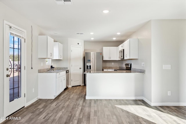 kitchen featuring light hardwood / wood-style floors, white cabinetry, light stone countertops, and stainless steel appliances