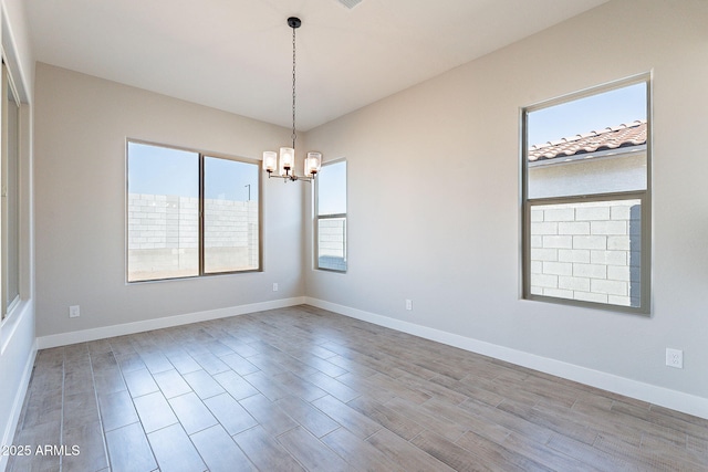 unfurnished room featuring a wealth of natural light and an inviting chandelier