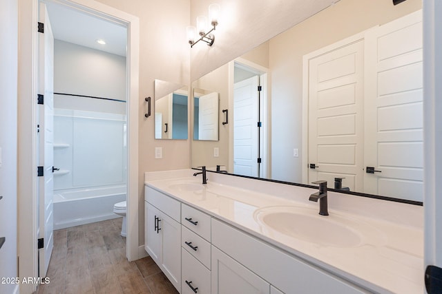 full bathroom featuring hardwood / wood-style floors, vanity, toilet, and tub / shower combination