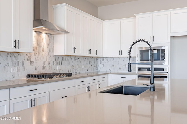 kitchen featuring tasteful backsplash, white cabinets, and wall chimney exhaust hood