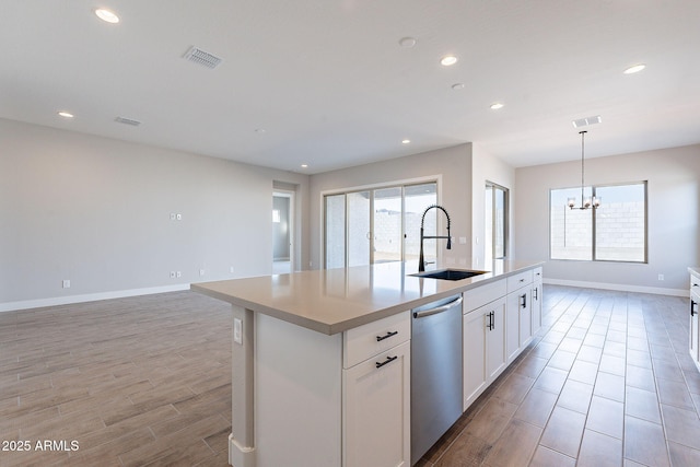 kitchen with white cabinets, sink, a notable chandelier, dishwasher, and an island with sink