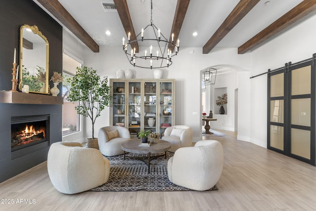 living area featuring light wood-type flooring, a barn door, visible vents, and arched walkways