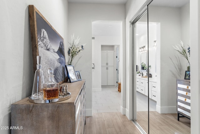 corridor featuring light wood-type flooring, visible vents, and baseboards