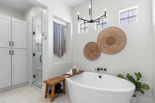 bathroom featuring a soaking tub, a shower stall, and an inviting chandelier