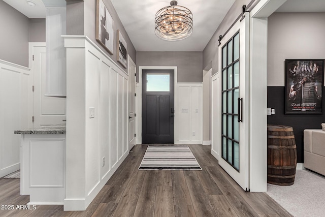 11385 N Luckenbach St, Surprise, AZ 85388 - entrance foyer featuring dark wood finished floors, a barn door, a chandelier, and a wainscoted wall