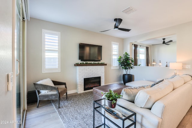 living room featuring plenty of natural light, ceiling fan, a fireplace, and light hardwood / wood-style flooring