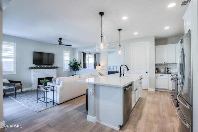 kitchen featuring white cabinetry, sink, pendant lighting, a center island with sink, and appliances with stainless steel finishes