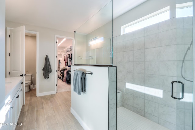 bathroom featuring wood-type flooring, vanity, a shower with shower door, and toilet