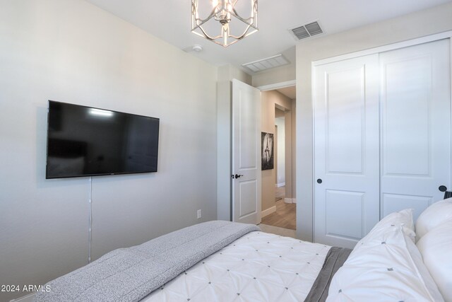 bedroom with a closet, hardwood / wood-style floors, and a notable chandelier