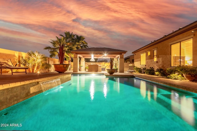 pool at dusk featuring a gazebo and a patio