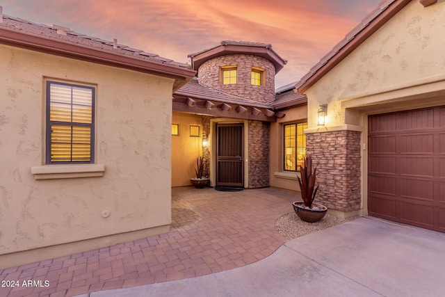 exterior entry at dusk featuring a garage