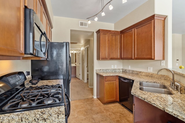 kitchen featuring a sink, light stone counters, visible vents, black appliances, and brown cabinets