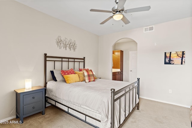 bedroom featuring light carpet, ensuite bath, baseboards, visible vents, and arched walkways