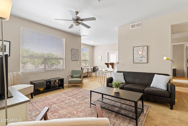 living area featuring light carpet, visible vents, and a ceiling fan