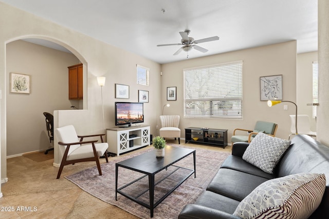 living room with baseboards, arched walkways, light tile patterned floors, and a ceiling fan