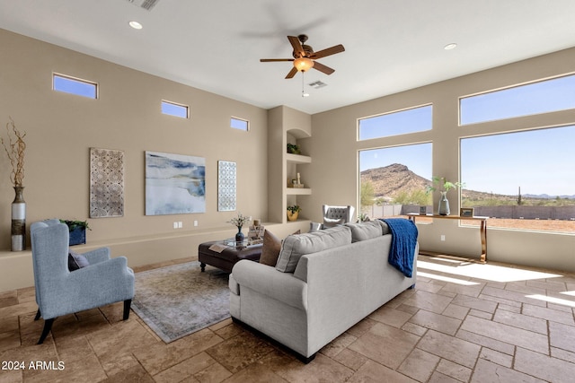 living room featuring built in shelves, ceiling fan, and a mountain view