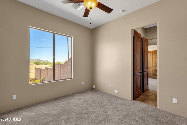 unfurnished bedroom with multiple windows, ceiling fan, and light colored carpet