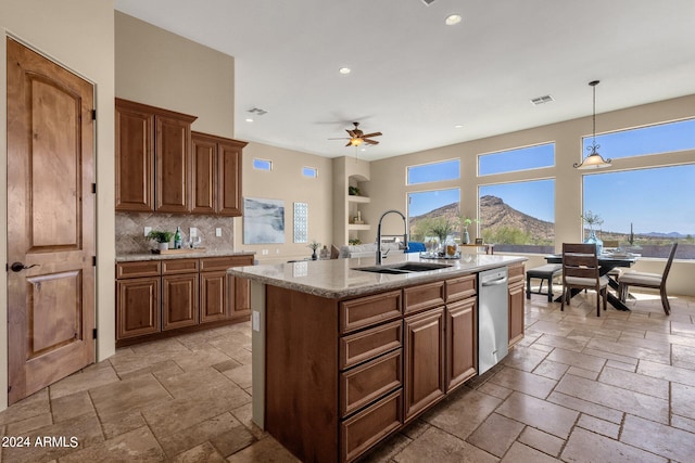 kitchen with a mountain view, sink, an island with sink, backsplash, and ceiling fan